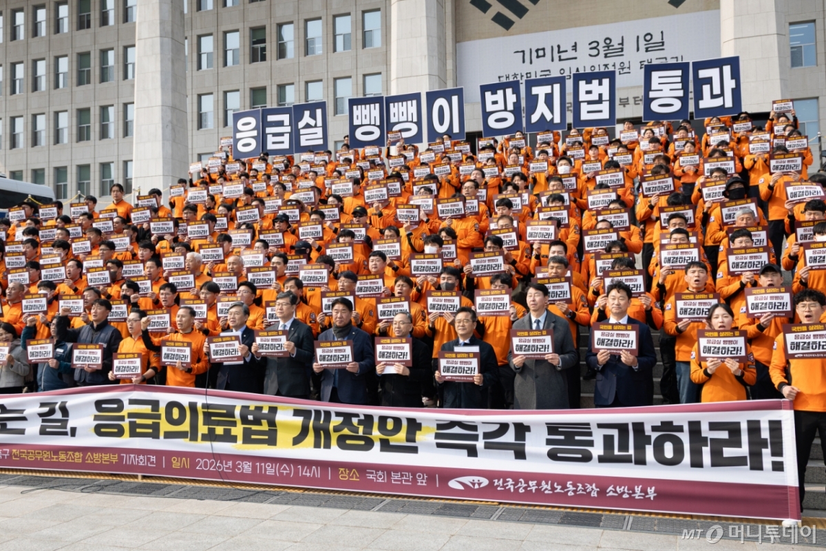 (서울=뉴스1) 유승관 기자 = 전국공무원노동조합 소방본부 조합원들과 여야 의원들이 11일 서울 여의도 국회 본청 앞에서 열린 응급실 뺑뺑이 방지법(응급의료법 개정안) 통과 촉구 기자회견에서 구호를 외치고 있다. 2026.3.11/뉴스1  Copyright © 뉴스1. All rights reserved. 무단 전재 및 재배포,  AI학습 이용 금지. /사진=(서울=뉴스1) 유승관 기자