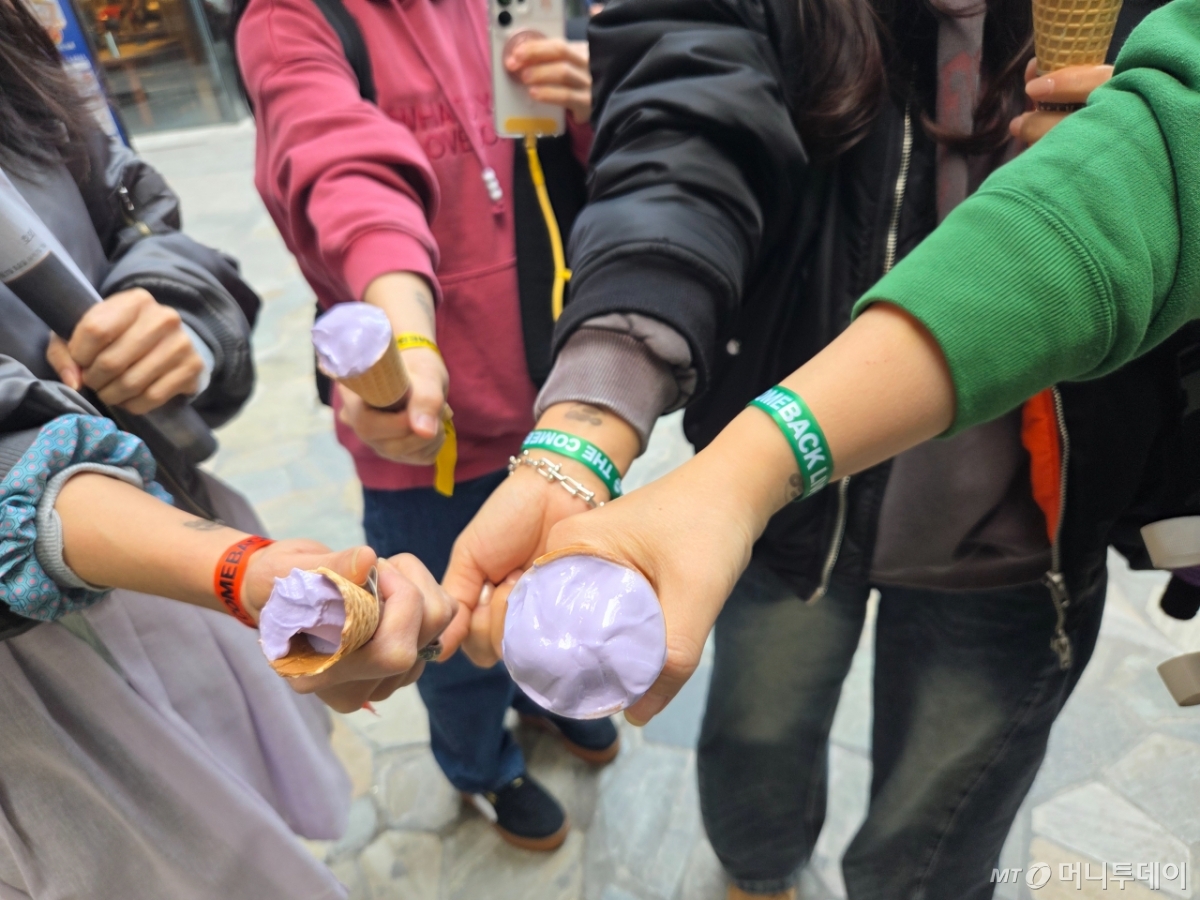 이모씨와 아미들이 BTS 광화문 공연 입장 팔찌를 착용한 채 아이스크림을 들어보이는 모습./사진=김서현 기자.