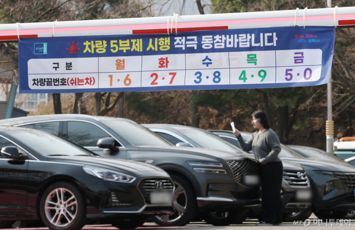 (군포=뉴스1) 김영운 기자 = 에너지 수급 위기 대응으로 공공부문 차량 5부제 전면 시행을 하루 앞둔 가운데 24일 경기 군포시 금정동 군포시청 직원주차장에서 관계자들이 차량 5부제 협조 안내문을 부착하고 있다. 군포시는 최근 중동 지역 긴장 고조로 국제 유가 변동성이 커지면서 공공 부문이 에너지 절약에 앞장서기 위해 지난 19일부터 '공직자 차량 5부제'를 시행하고 있다. 2026.3.24/뉴스1 Copyright © 뉴스1. All rights reserved. 무단 전재 및 재배포, AI학습 이용 금지. /사진=(군포=뉴스1) 김영운 기자