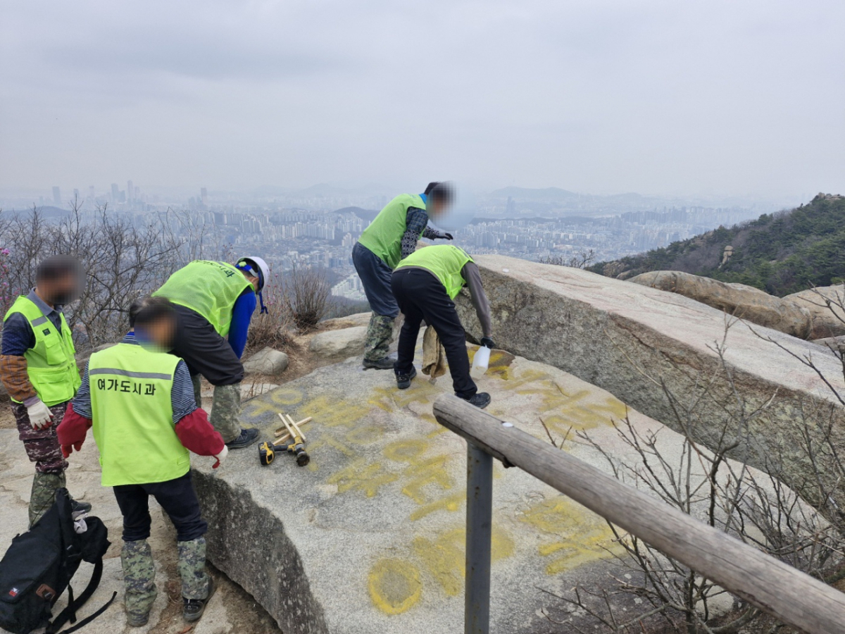 낙서로 인해 훼손된 바위를 복원 중인 모습. /사진=관악구청 제공.