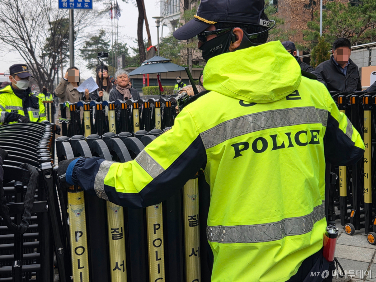 1일 수요집회가 종료된 지 10여분 지난 시점 경찰이 소녀상 주위로 다시 바리케이드를 설치하고 있다. 소녀상의 조각가인 김서경 작가가 이를 아련하게 바라보고 있는 모습./사진=김서현 기자.