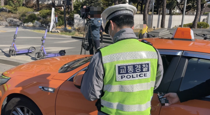 7일 오전 서울 서대문구 연세대 교차로에서 교통 경찰이 신호위반을 한 택시 기사에게 범칙금을 부과하는 모습./사진=이현수 기자.