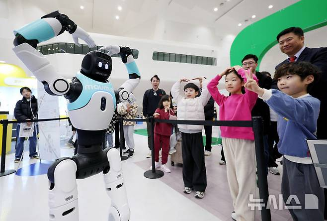 지난 2월 28일 서울 중구 동대문디자인플라자(DDP) 아트홀에서 열린 '서울AI페스티벌 2026'에서 아이들이 국내 최초로 일반에 공개되는 완전 자율형 민첩 로봇 '우치봇'과 머리 위로 하트 모양을 만들고 있다./사진=뉴시스