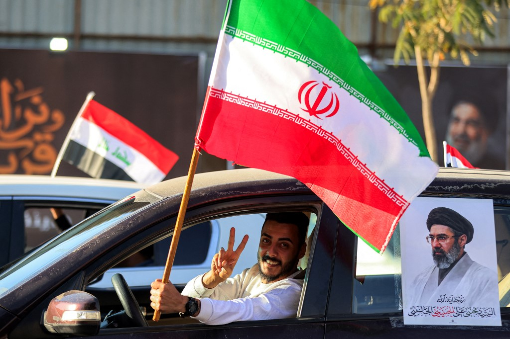 8일(현지시간) 이라크 바그다드 타흐리르 광장에서 미국과 이란의 휴전을 환영하는 행사에서 한 운전자가 이란 국기를 흔들며 손으로 V자를 그리고 있다./AFPBBNews=뉴스1