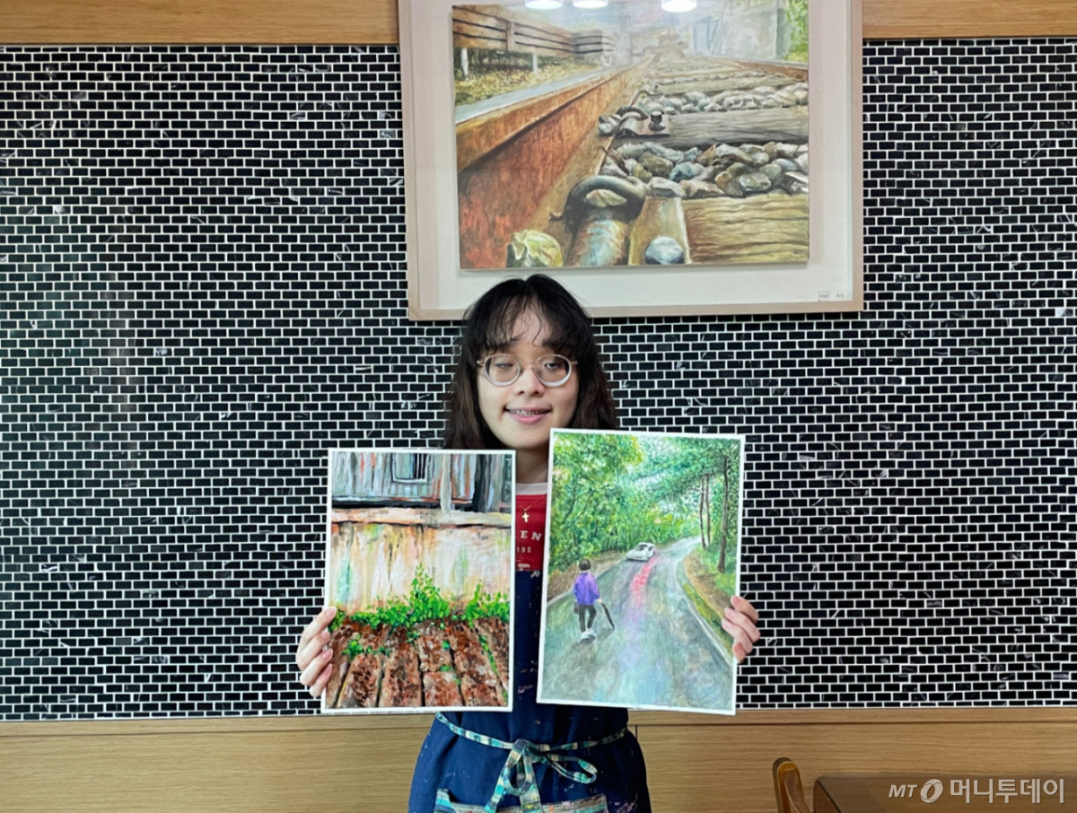 유진 작가가 직접 그린 수채화 작품들을 들고 있는 모습./사진=이현수 기자.