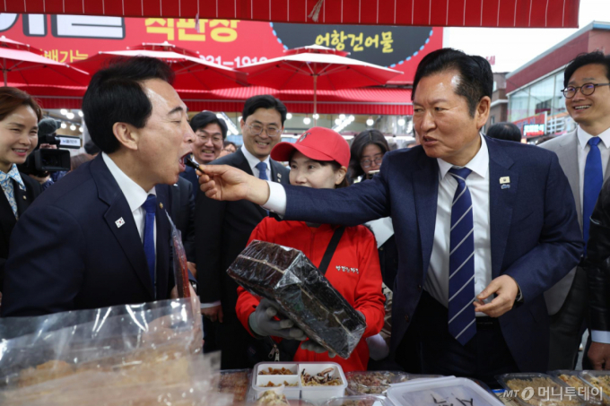  정청래 더불어민주당 대표가 20일 충남 보령 대천항수산시장을 방문, 건어물을 살피던 중 박수현 충남도지사 후보에게 돌김을 먹여주고 있다. /사진=뉴시스