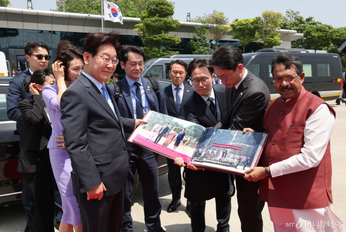 (뉴델리(인도)=뉴스1) 이재명 기자 = 인도 국빈 방문을 마친 이재명 대통령과 김혜경 여사가 21일(현지시간) 뉴델리 팔람 군비행장에서 베트남행 공군 1호기 탑승 전 사진첩을 선물 받고 있다. 2026.4.21/뉴스1  Copyright © 뉴스1. All rights reserved. 무단 전재 및 재배포,  AI학습 이용 금지. /사진=(뉴델리(인도)=뉴스1) 이재명 기자