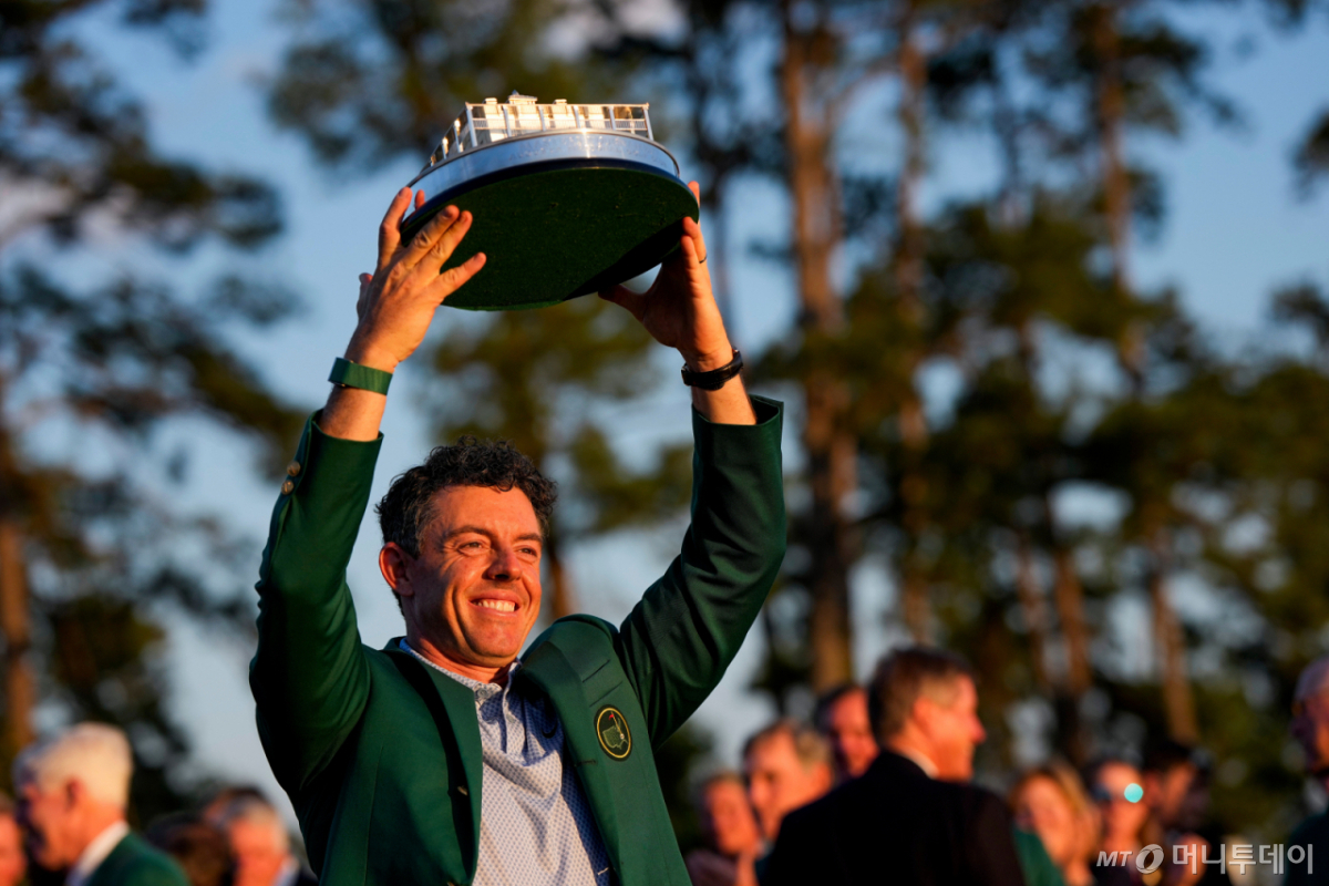 [오거스타=AP/뉴시스] 로리 매킬로이(북아일랜드)가 12일(현지 시간) 미 조지아주 오거스타 내셔널 골프클럽에서 열린 미국프로골프(PGA) 투어 제90회 마스터스 토너먼트 정상에 올라 그린 재킷을 입고 트로피를 들어 올리고 있다. 매킬로이는 최종 합계 12언더파 276타로 '와이어 투 와이어' 우승을 차지하며 대회 2연패를 기록했다. 2연패는 타이거 우즈 이후 24년 만에 나온 역대 4번째 대기록이다. 2026.04.13. /사진=민경찬