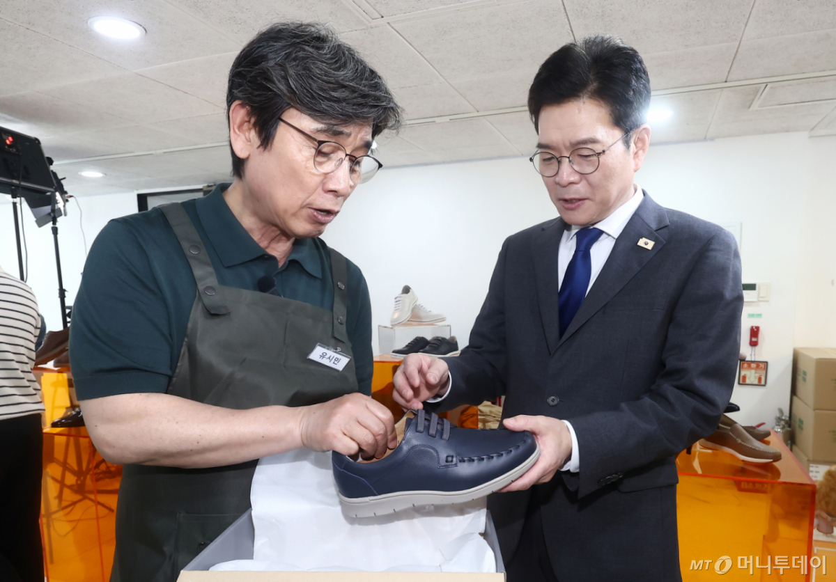 (서울=뉴스1) 김민지 기자 = 정원오 더불어민주당 서울시장 후보가 24일 오후 서울 성동구 언더스탠드에비뉴에 마련된 청각장애인 수제화 브랜드 '아지오' 매장 오픈 행사에 참석해 일일 아르바이트생으로 나선 유시민 작가로부터 신발을 전달받고 있다.. 2026.4.24/뉴스1  Copyright © 뉴스1. All rights reserved. 무단 전재 및 재배포,  AI학습 이용 금지. /사진=(서울=뉴스1) 김민지 기자