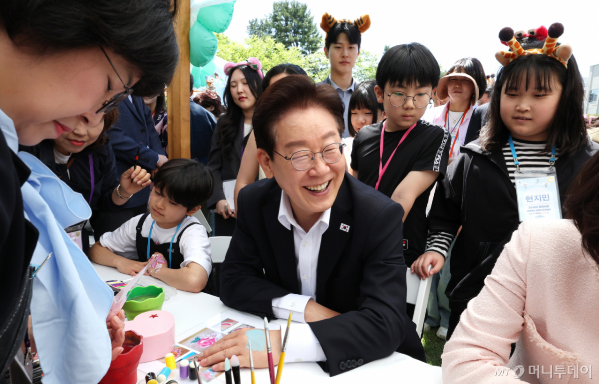[서울=뉴시스] 최동준 기자= 이재명 대통령이 5일 청와대 녹지원에서 열린 2026 어린이날 초청행사에 참석한 어린이들과 함께 손등에 페이스 페인팅을 받고 있다. 2026.05.05. photocdj@newsis.com /사진=