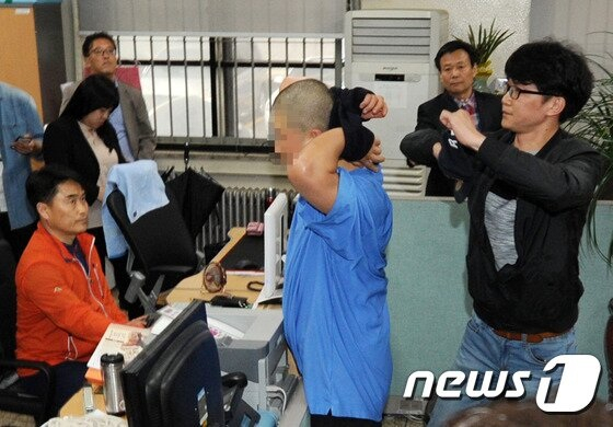 아버지를 살해한 아들이 갑자기 모자를 벗으며 얼굴을 공개하자 경찰 관계자가 다급히 모자를 씌우는 모습. /사진=뉴스1