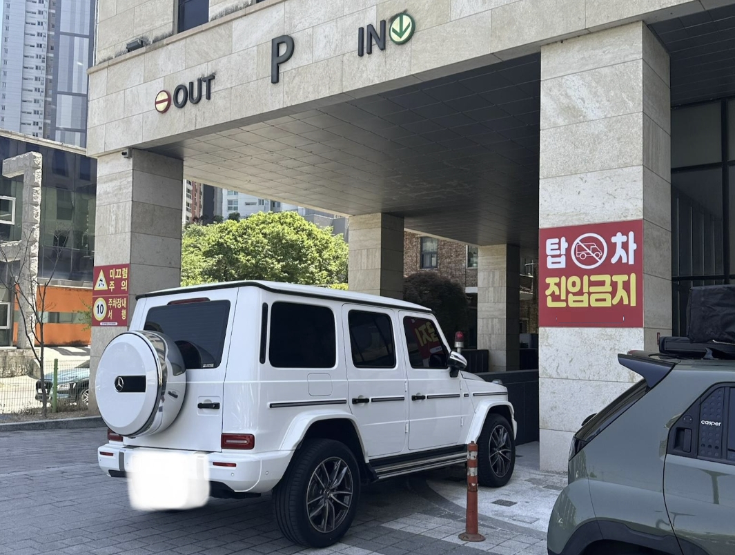 최근 온라인 커뮤니티에 공개된 사진에 따르면, 고가의 SUV 차량이 지하주차장 하행 차로 초입과 보행로 경계에 걸쳐 주차되어 있다. 이로 인해 입출차 차량들이 중앙선을 침범해 우회해야 하는 상황이며, 특히 시야가 확보되지 않는 코너 지점이라 사고 위험이 높은 것으로 전해졌다/사진=온라인 커뮤니티 갈무리