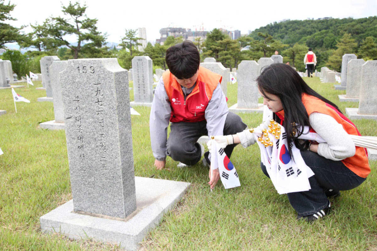 SKC 봉사단이 22일 국립서울현충원에서 태극기 꽂기와 묘역 주변 잡초 제거, 비석 닦기 등 환경 정화 작업을 실시하고 있다. /사진=SKC