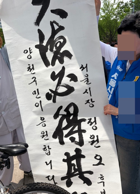 25일 서울 양천구 목동 현대백화점 앞에서 한 남성이 "대덕필득기위"라고 적힌 붓글씨를 들고 등장했다. /사진=김지은 기자