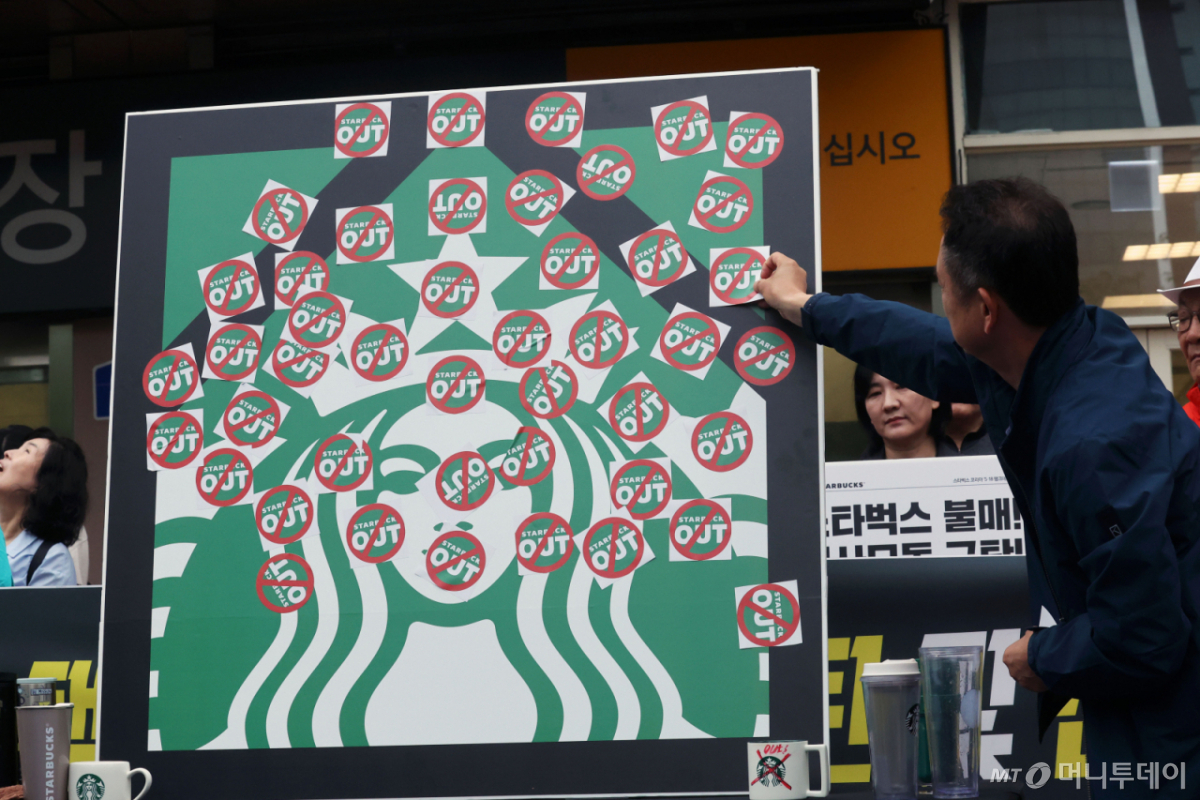 (광주=뉴스1) 조수민 수습기자 = 오월을 사랑하는 모임 등 광주시민단체 들이 21일 오후 광주 서구 광천동 이마트 광주점 앞에서 스타벅스의 '5·18 탱크데이' 마케팅을 규탄하는 기자회견을 열고 스타벅스 OUT 스티커를 붙이고 있다. 2026.5.21/뉴스1 Copyright © 뉴스1. All rights reserved. 무단 전재 및 재배포, AI학습 이용 금지. /사진=(광주=뉴스1) 조수민 수습기자