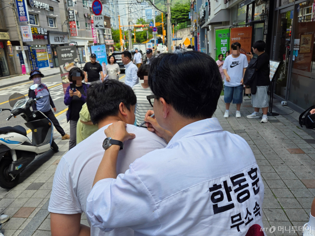 한동훈 무소속 부산 북갑 국회의원 후보가 25일 만덕동에서 한 남학생 요청으로 옷에 사인을 해주고 있다./사진=박상곤 기자