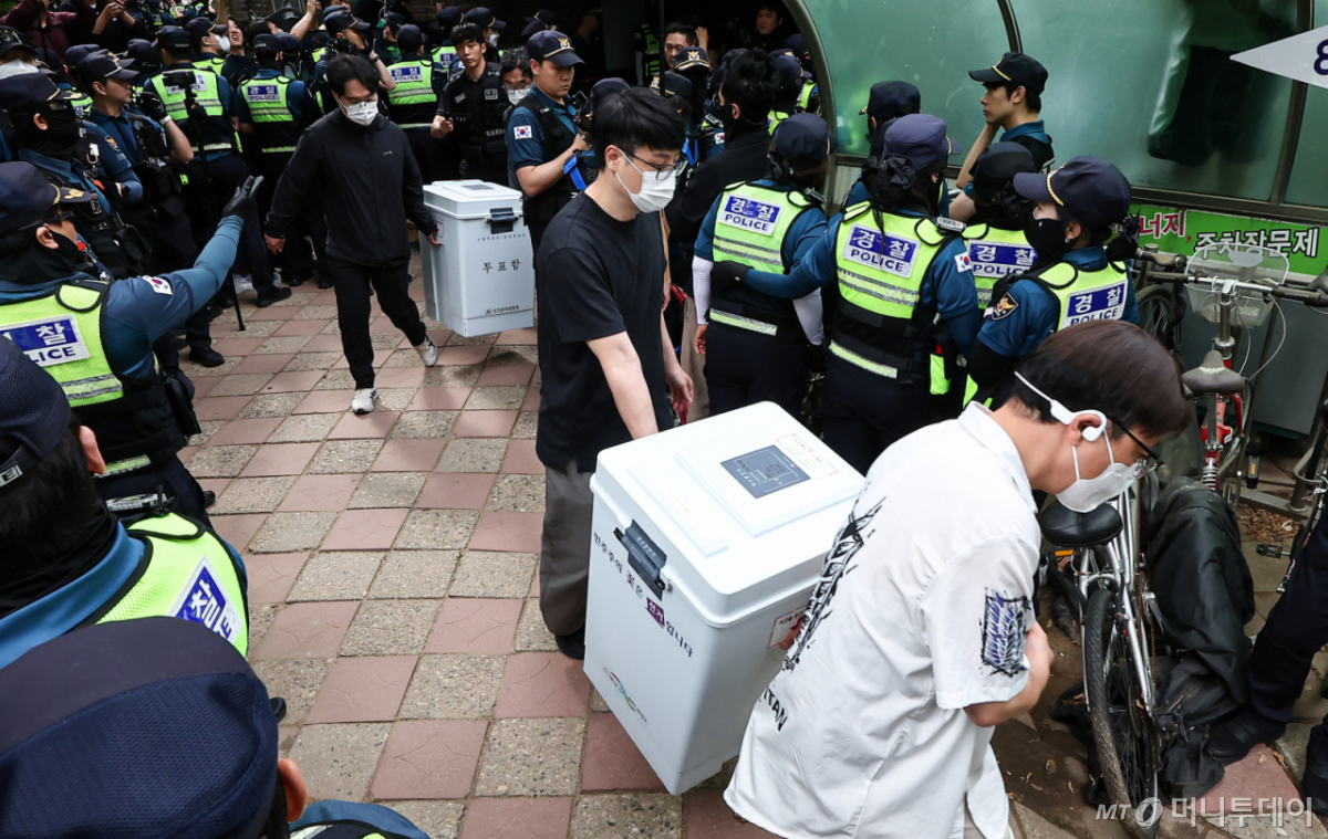 (서울=뉴스1) 김도우 기자 = 5일 '투표용지 부족' 사태가 발생한 서울 송파구 잠실7동 제2투표소 앞에서 서울시선관위 관계자들이 투표함을 이송하고 있다. 2026.6.5/뉴스1  Copyright © 뉴스1. All rights reserved. 무단 전재 및 재배포,  AI학습 이용 금지. /사진=(서울=뉴스1) 김도우 기자