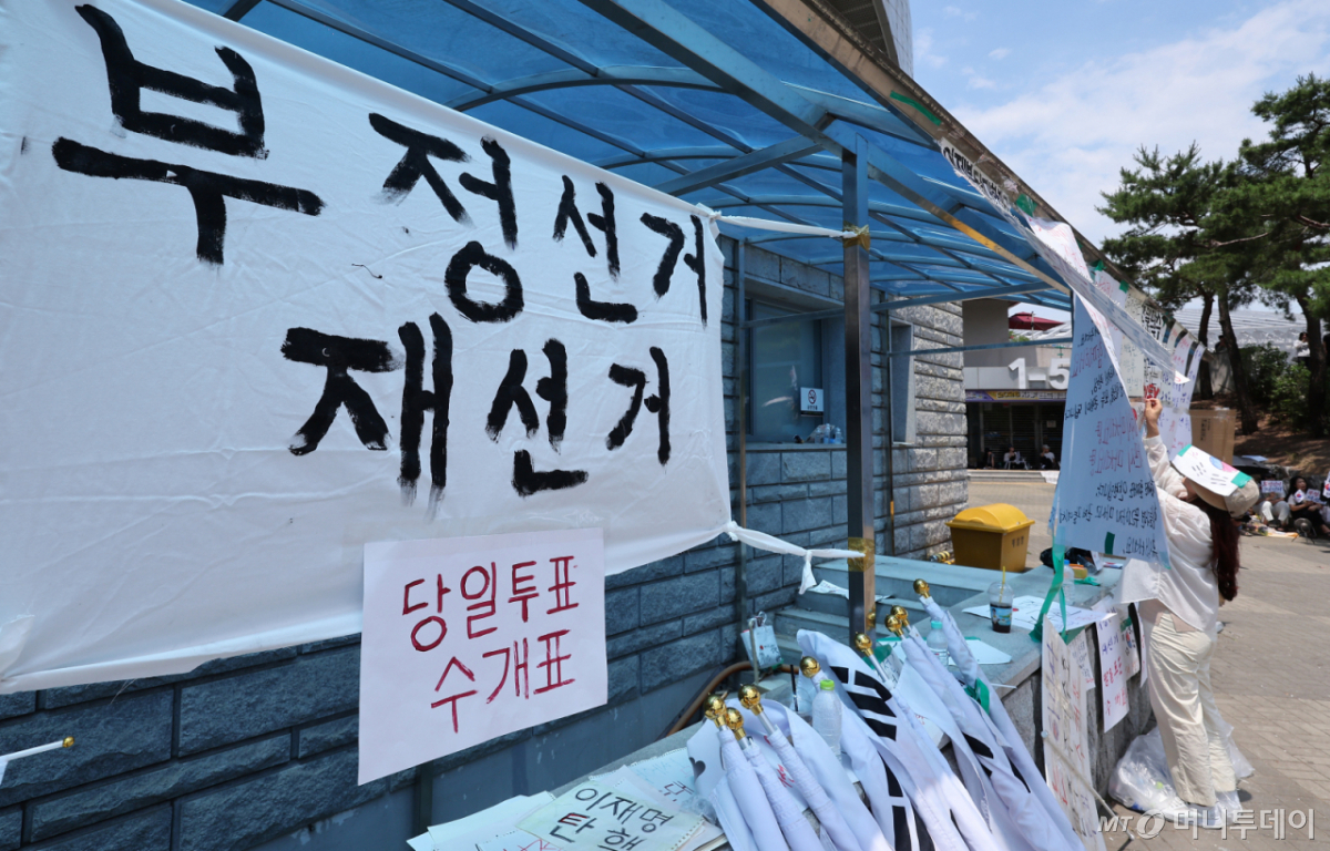 (서울=뉴스1) 김성진 기자 = 제9회 전국동시지방선거 투표용지 부족 사태에 반발한 시민들이 9일 서울 송파구 올림픽공원 핸드볼경기장에 설치된 개표소 앞에서 재선거를 촉구하며 피켓을 붙이고 있다. 2026.6.9/뉴스1 Copyright © 뉴스1. All rights reserved. 무단 전재 및 재배포, AI학습 이용 금지. /사진=(서울=뉴스1) 김성진 기자