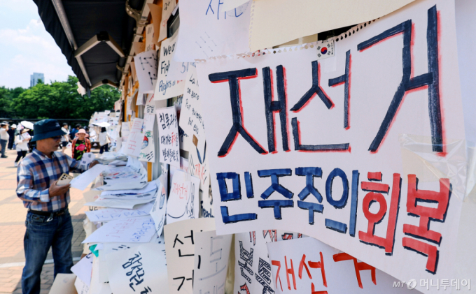 (서울=뉴스1) 이호윤 기자 = 제9회 전국동시지방선거 투표용지 부족 사태를 규탄하며 재선거를 요구하는 집회가 계속되는 10일 서울 송파구 올림픽공원 핸드볼경기장 인근 티켓 부스에 재선거를 요구하는 메시지가 붙어 있다. 2026.6.10/뉴스1 Copyright (C) 뉴스1. All rights reserved. 무단 전재 및 재배포, AI학습 이용 금지. /사진=(서울=뉴스1) 이호윤 기자