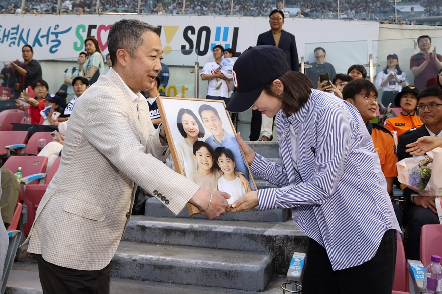 박정원(왼쪽) 회장이 2025년 6월 24일 '두산베어스 소방가족의 날' 행사에서 2018년 순직한 고(故) 심문규 소방장 유가족에게 AI 복원 가족 사진 및 기념품을 전달하고 있다.  /사진=두산 베어스