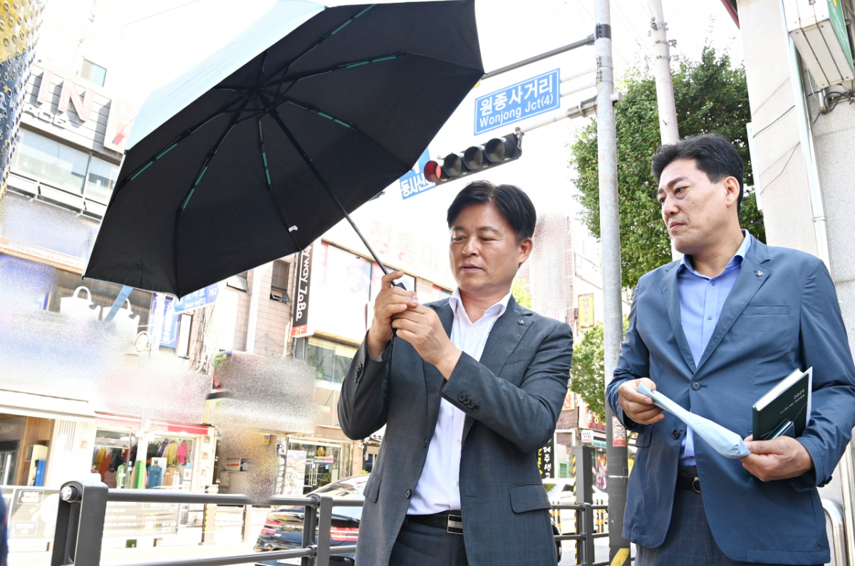 조용익 부천시장(왼쪽)이 '폭염 속 그늘' 사업에 사용되는 우산을 꼼꼼히 살펴보고 있다./사진제공=부천시