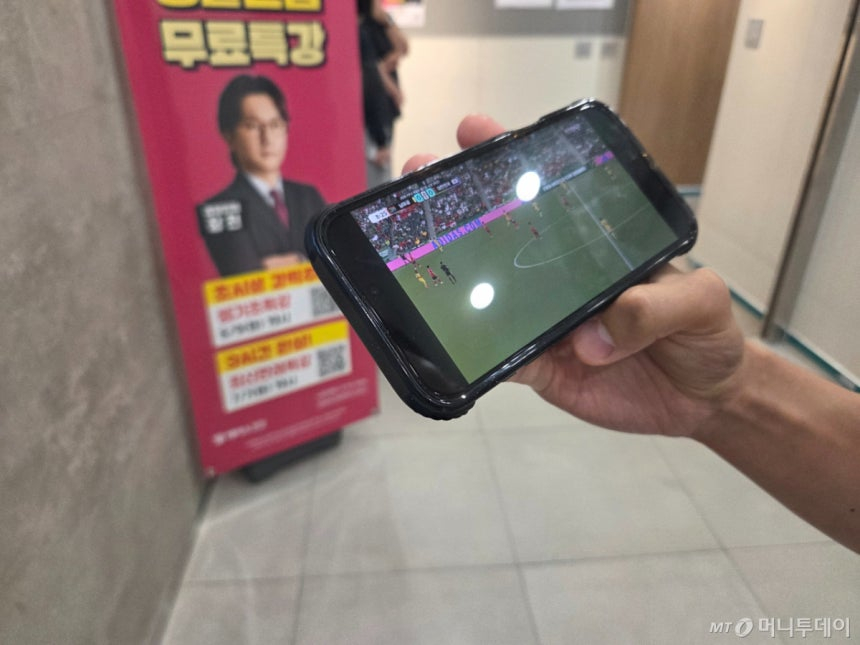 한 수험생이 학원 독서실을 눈앞에 두고 핸드폰으로 축구 경기를 시청하고 있는 모습./사진=김서현 기자.