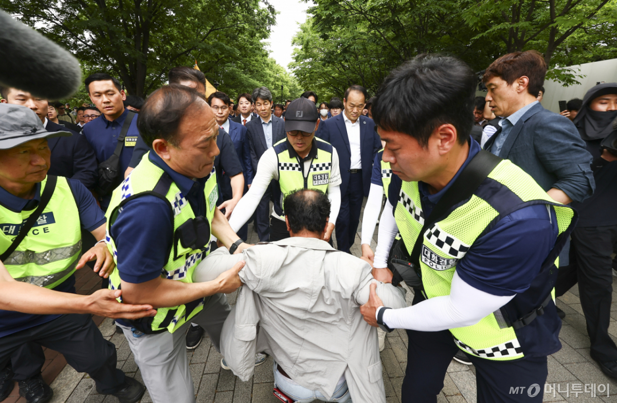 (서울=뉴스1) 국회사진기자단 = 6·3 지방선거 투표용지 부족 사태를 조사 중인 국회 국정조사특별위원회 윤상현 위원장과 위원들이 2일 서울 송파구 올림픽공원 내 개표소 내부로 이동하는 도중 한 시위 참가자가 앞으로 달려들고 있다. 2026.7.2/뉴스1 Copyright © 뉴스1. All rights reserved. 무단 전재 및 재배포, AI학습 이용 금지. /사진=(서울=뉴스1) 국회사진기자단