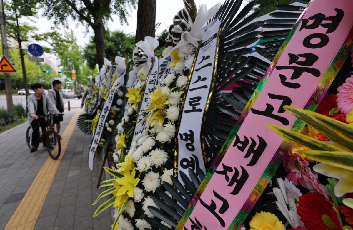 지난 2일 서울 강동구 배재고등학교 앞에서 학생들이 배재고 야구부를 비판하는 근조화환과 응원하는 화환들을 보고 있다./사진=뉴스1.