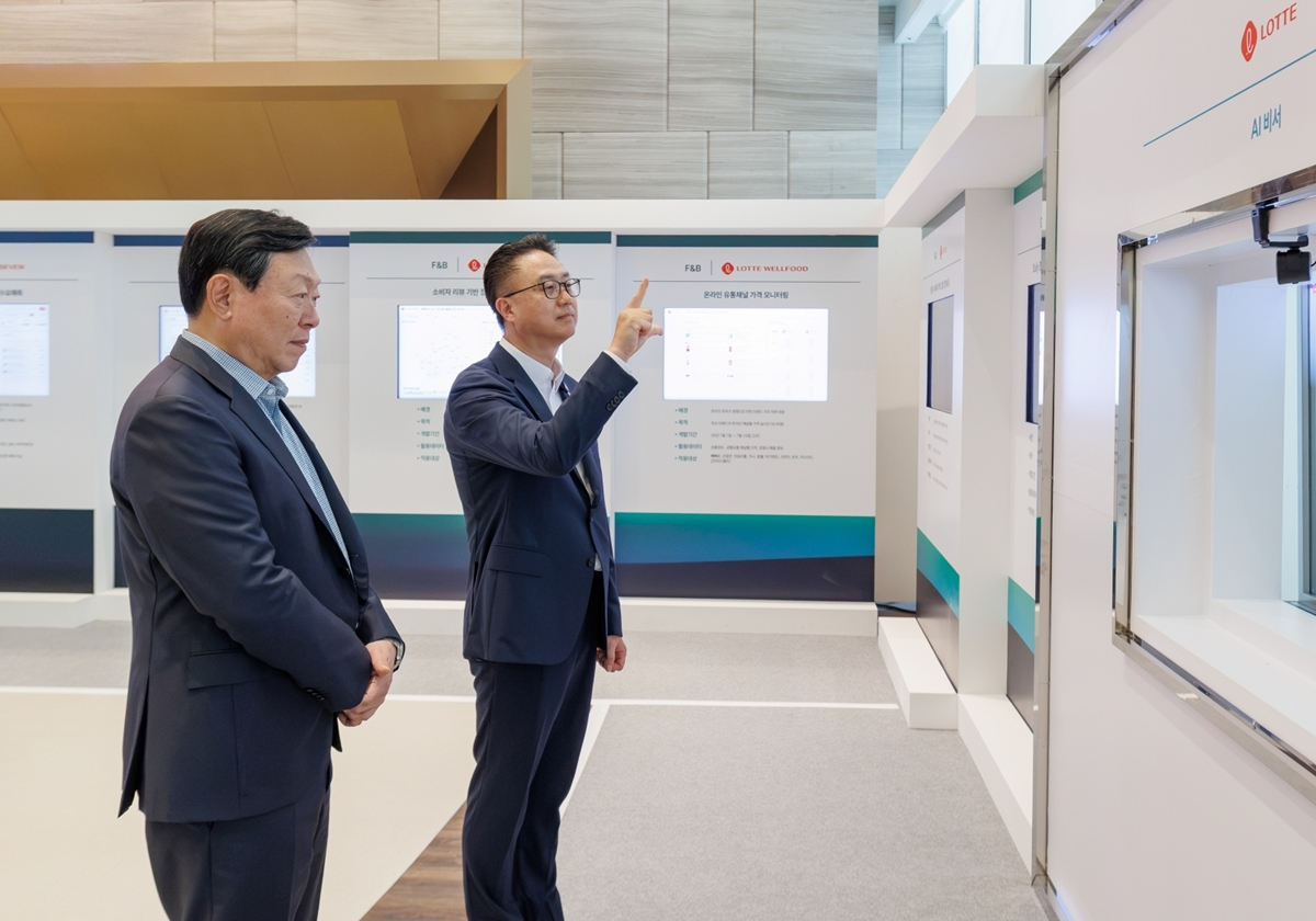 롯데는 15일 롯데월드타워에서 '2026 하반기 VCM'을 개최했다. 본 회의에 앞서 그룹 AX 추진 현황 및 사례를 소개하는 'AI 에이전트 전시'를 진행했다. 신동빈 롯데 회장(왼쪽)이 황민재 롯데지주 경영혁신실장(오른쪽)으로부터 음성과 모션 인식 기반 'AI 비서'에 대한 설명을 듣고 있다./사진제공=롯데