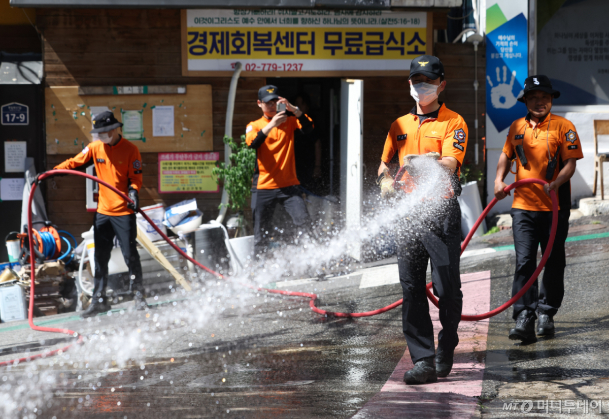 서울 용산소방서 후암119안전센터 소방대원들이 지난 29일 오후 서울 용산구 동자동 쪽방촌에서 순찰 중 지면 온도를 낮추기 위해 살수작업을 하고 있다. /사진=뉴시스