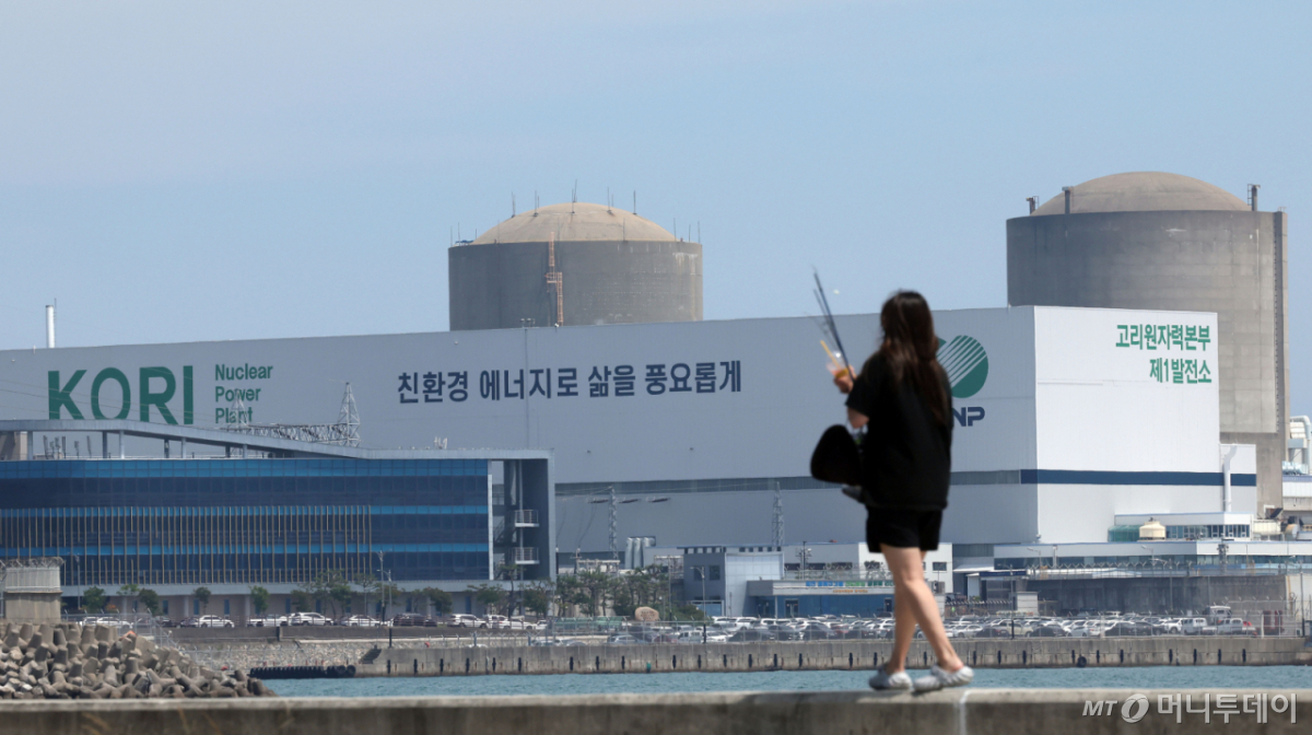 부산 기장군이 0.7GW급 국내 첫 소형모듈원자로(SMR) 1기의 건설 후보지로 선정된 가운데 18일 기장군의 한 방파제를 지나는 시민 뒤로 고리원전 1~2호기가 보이고 있다. 2026.06.18. /사진=뉴시스