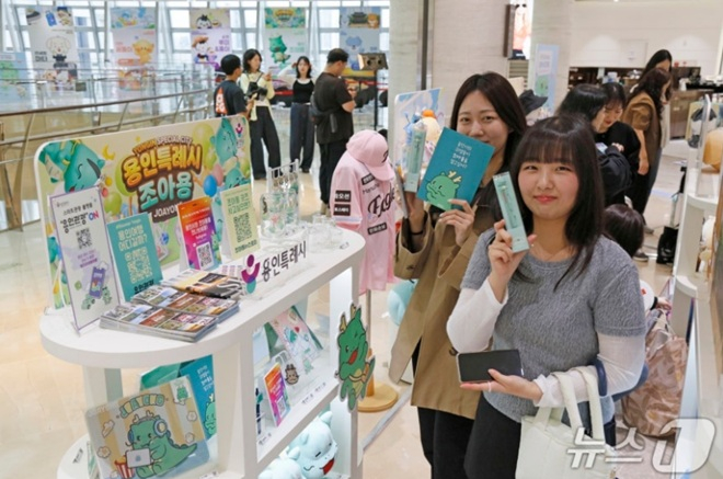 외국 관광객이 서울 롯데면세점 월드타워점 ‘K-공공캐릭터 굿즈 팝업존’에서 용인시 대표 캐릭터 조아용 굿즈를 들고 기념촬영을 하고 있는 모습. /사진=뉴스1(용인시 제공)
