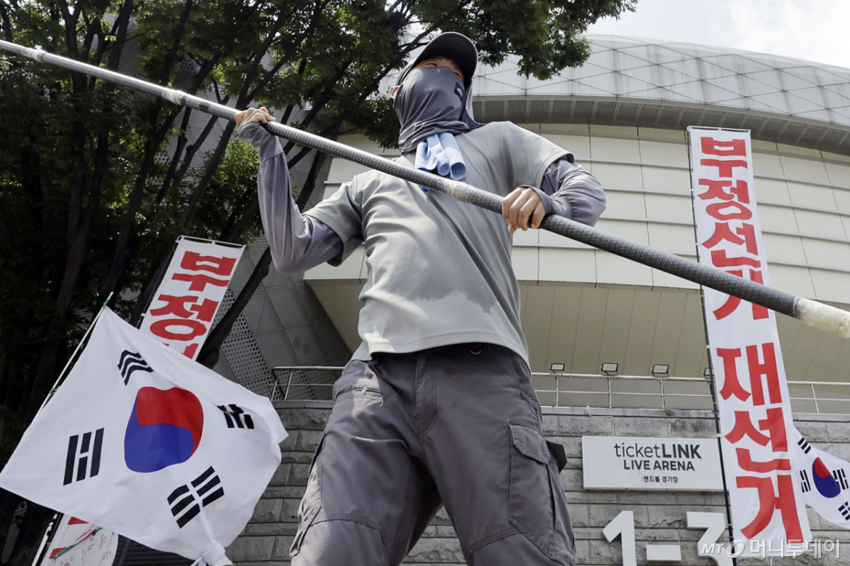 [서울=뉴시스] 최동준 기자 = 투표용지 부족 사태에 항의하는 개표소 시위가 54일째 이어지고 있는 28일 서울 송파구 올림픽공원 핸드볼 경기장 앞에서 시위 참가자가 태극기를 흔들고 있다. 2026.07.28. photocdj@newsis.com /사진=최동준