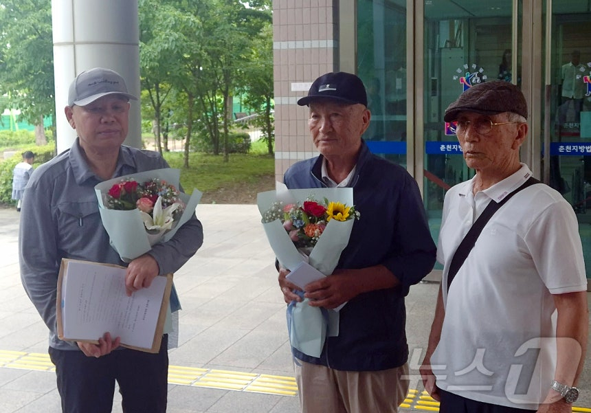 1969년 '동해안고정간첩단 사건'(일명 속초간첩단 사건)으로 간첩 누명을 썼던 납북귀환어부들의 유족들이 지난 13일 춘천지법 강릉지원 앞에서 재심 무죄 판결문과 꽃다발을 들고 기념 촬영을 하고 있다./사진=뉴스1