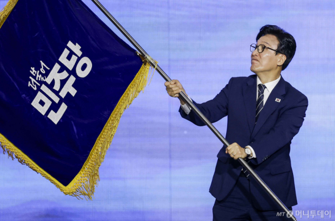 김민석 신임 더불어민주당 당대표가 17일 대전 유성구 대전컨벤션센터 제2전시장에서 열린 더불어민주당 제3차 정기전국당원대회에서 당기를 흔들고 있다./대전=뉴시스