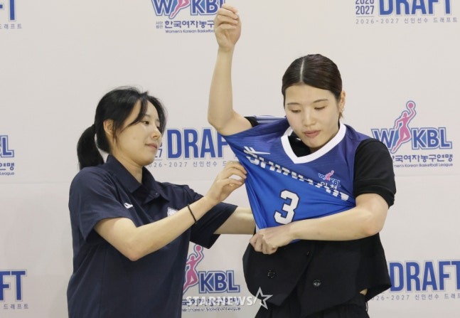 2026~2027시즌 WKBL 신인 선수 드래프트가 19일 청주시 청주체육관에서 열렸다. 가네다 마나(오사카 인간과학 대학교)RK 1라운드 1순위로 신한은행에 지명된 후 최윤아 감독의 도움을 받아 유니폼을 입고 있다. /사진=김진경 대기자.