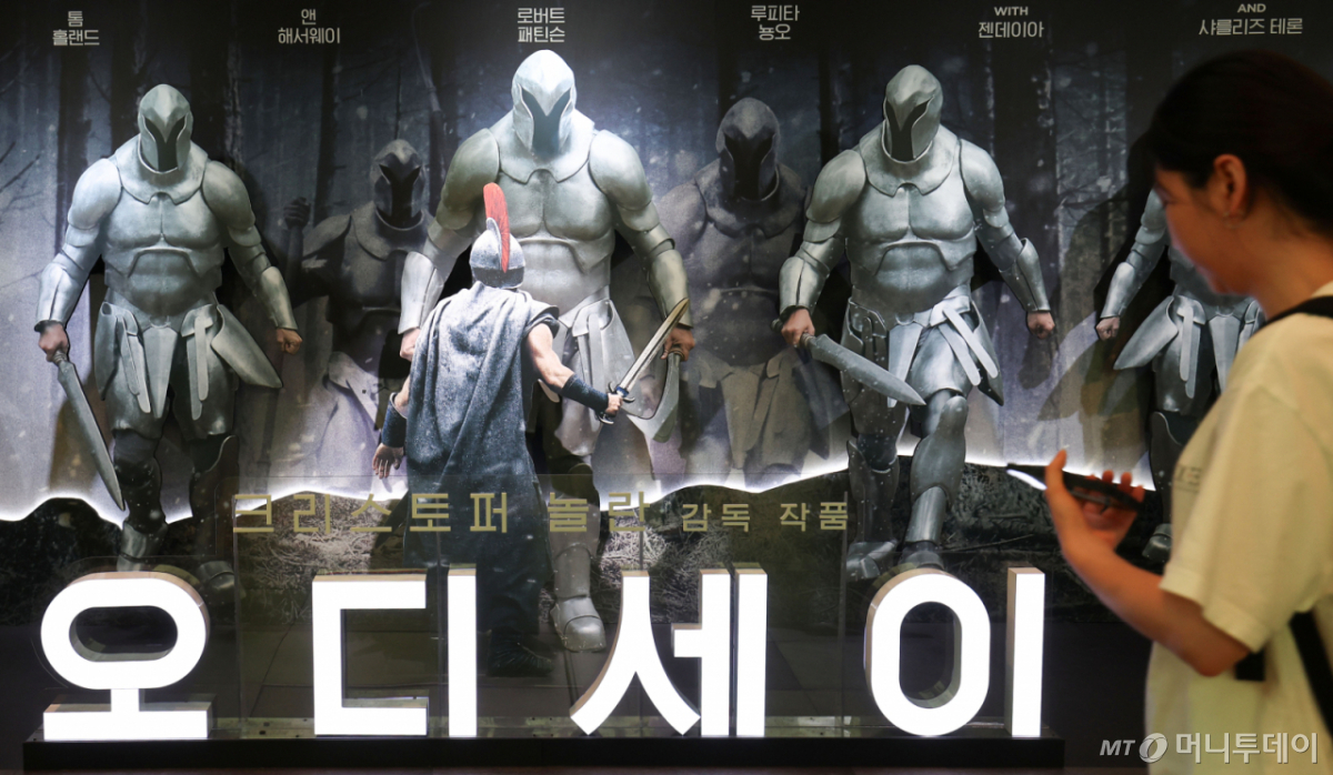 영화 ‘오디세이’(감독 크리스토퍼 놀란)가 누적 관객 500만명을 돌파한 17일 서울 시내 한 영화관을 찾은 관람객들이 ‘오디세이’ 홍보물 앞을 지나고 있다.  배급사 유니버설 픽쳐스에 따르면 지난 5일 개봉한 ‘오디세이’는 개봉 13일째인 이날 누적 관객 500만명을 넘어섰다. 전날 400만 관객을 돌파한 지 하루 만이다.  ‘오디세이’는 호메로스의 대서사시 ‘오디세이아’를 바탕으로 트로이 전쟁을 마친 영웅 오디세우스(맷 데이먼 분)가 아내 페넬로페(앤 해서웨이 분)와 아들 텔레마코스(톰 홀랜드 분)에게 돌아가기 위해 겪는 여정을 그린 작품이다. /사진=뉴스1