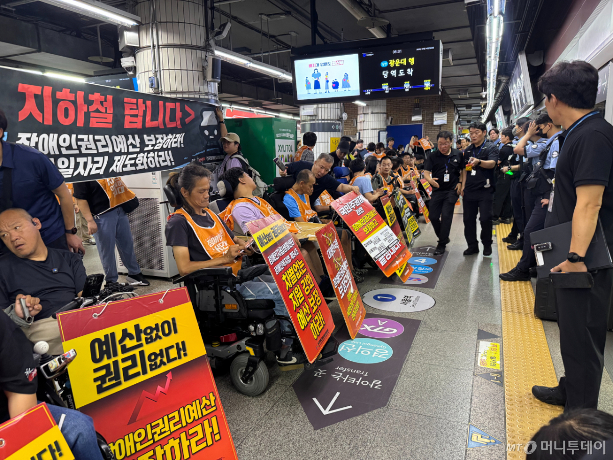 전국장애인차별철폐연대(전장연) 회원들이 24일 지하철 4호선 서울역사 안에서 장애인 권리예산 보장을 촉구하며 팻말을 들고 있다. /사진=조유진 기자