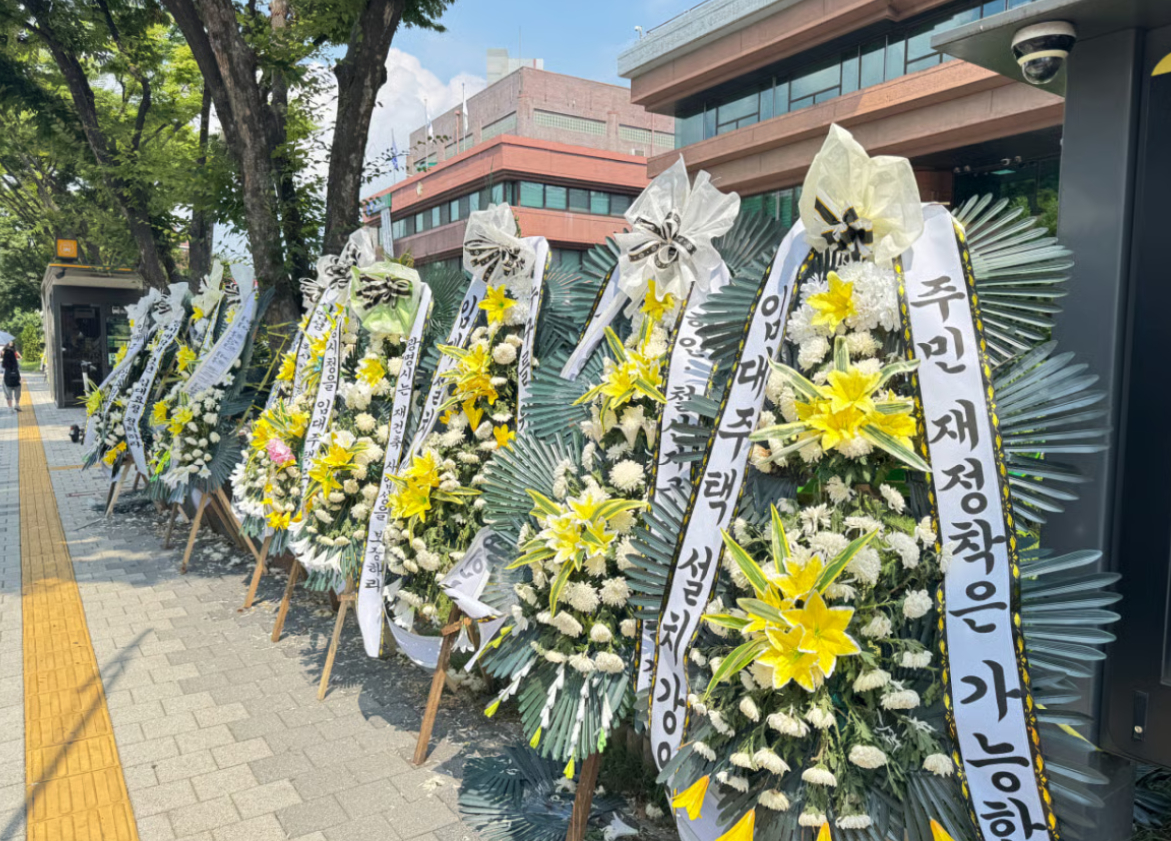 광명시청 정문 인근에 공공임대주택 반영 지침을 규탄하는 하안동 재건축 조합원들의 근조 화환이 줄지어 세워졌다./사진=권현수기자