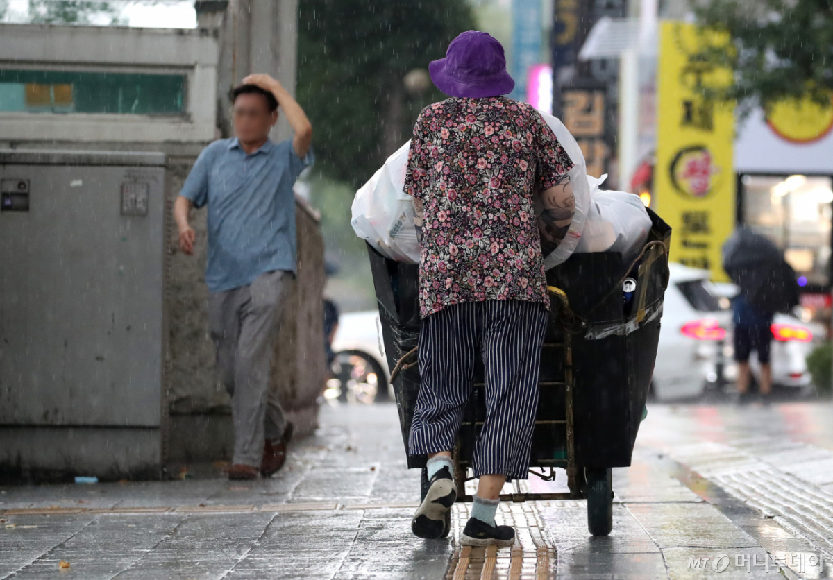 지난달 27일 오후 대구 수성구 달구벌대로 담티고개 인근에 천둥번개를 동반한 비가 내리는 가운데 우산도 쓰지 않은 노인이 재활용품을 수레 가득 담아 밀고 있다. /사진=뉴스1