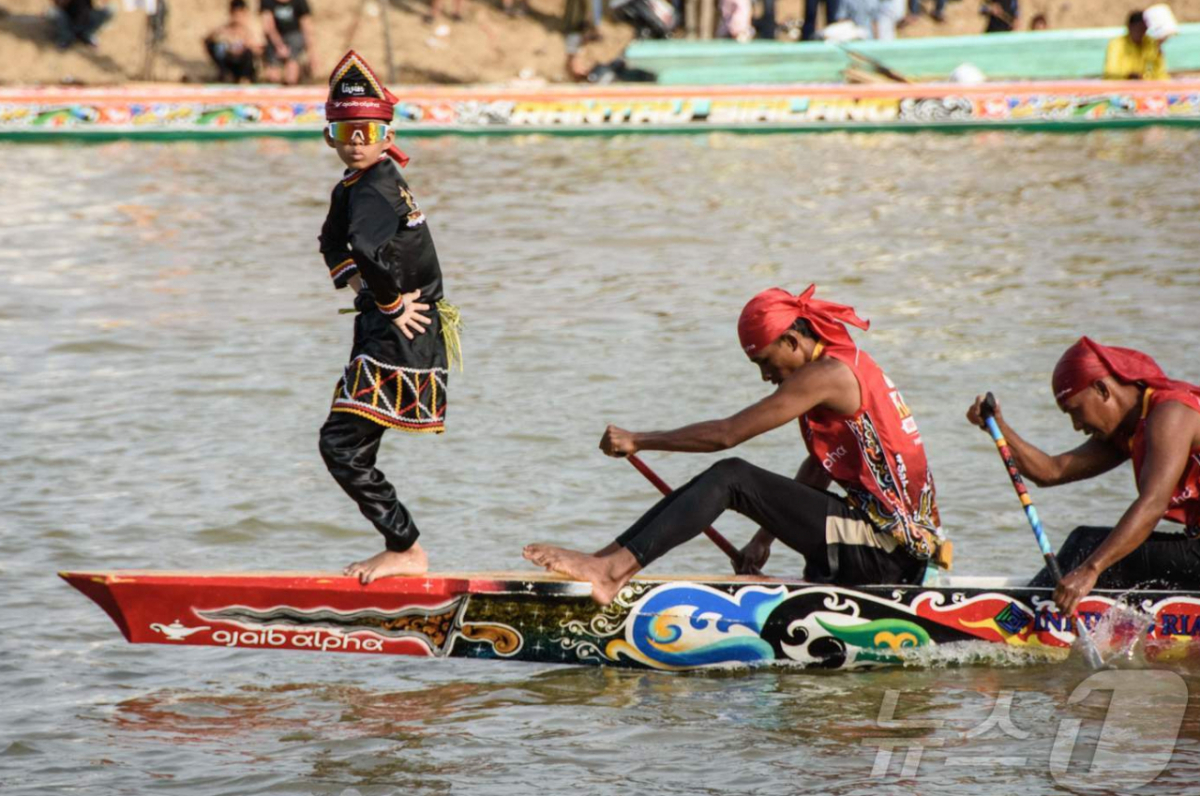 인도네시아 리아우주 쿠안탄강에서 열린 파추 잘루르(Pacu Jalur) 전통 보트 경주 축제중 뱃머리에서 춤을 추며 SNS에서 화제를 모은 11세 소년 레이얀 아르칸 디카(왼쪽)가 공연을 선보이고 있다. 2025.8.21 ⓒ AFP=뉴스1