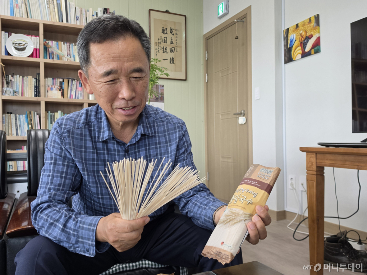 심상준 우리농촌살리기공동네트워크 대표가 지난 9일 전북 김제 우리농촌살리기공동네트워크 사무실에서 국산 밀로 만든 국수 제품과 면을 들어 보이고 있다. 이곳에서는 제분한 우리밀 밀가루를 이용해 국수를 직접 생산한다. /사진=이수현