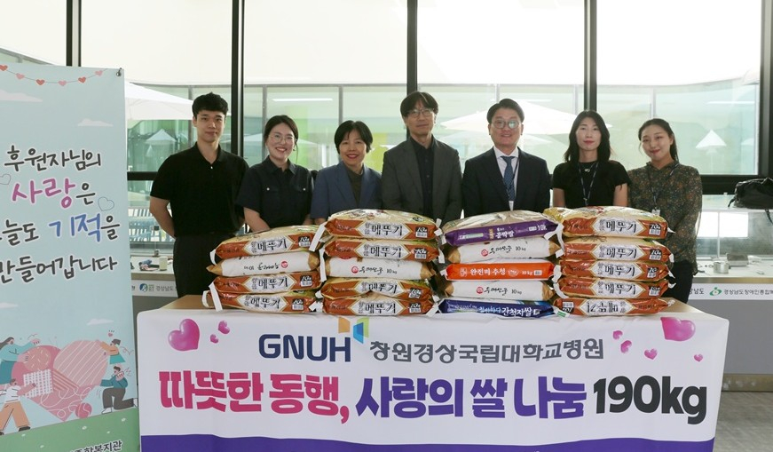 김현옥 창원경상국립대병원 진료처장(가운데)이 류학기 경남도장애인종합복지관장(왼쪽에서 5번째)에게 쌀을 전달하고 참석자와 기념촬영을 하고 있다./사진제공=창원경상국립대병원