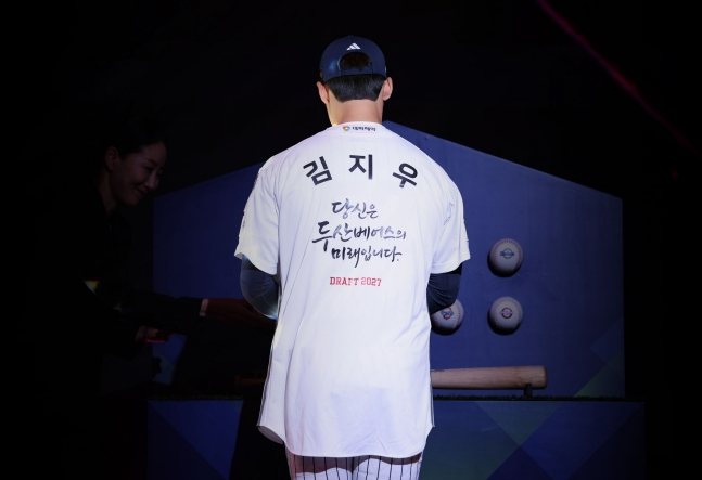 서울고  김지우가 21일 서울 롯데호텔 월드 크리스탈볼룸에서 열린 2027 KBO 신인드래프트에서 1라운드 2순위 지명을 받은 뒤 특별한 메시지가 새겨진 유니폼을 입고 있다. /사진=두산 베어스 제공
