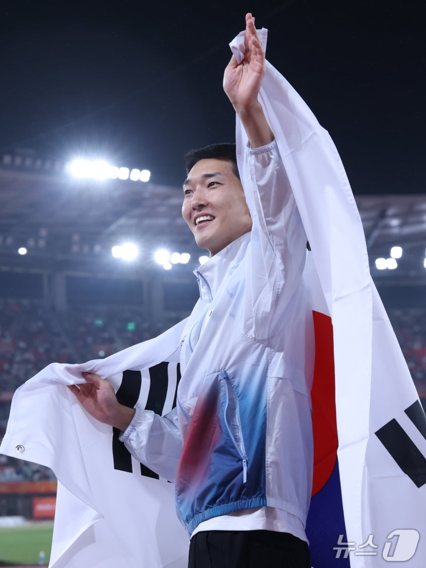 한국 육상 우상혁이 27일 나고야 미즈호공원 육상경기장에서 열린 2026 아이치·나고야 아시안게임 남자 높이뛰기 동메달을 확정한 뒤 태극기를 메고 세리머니를 하고 있다. /사진=뉴스1 제공
