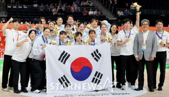 금메달을 따낸 농구 여자대표팀 선수들이 26일 일본 나고야 IG아레나에서 열린 2026 아이치·나고야 아시안게임 여자농구 대한민국과 일본의 금메달 결정전에서 승리한 후 금메달 목에 건 박수호 감독과 태극기세리머니를 하고 있다. /사진=강영조 선임기자
