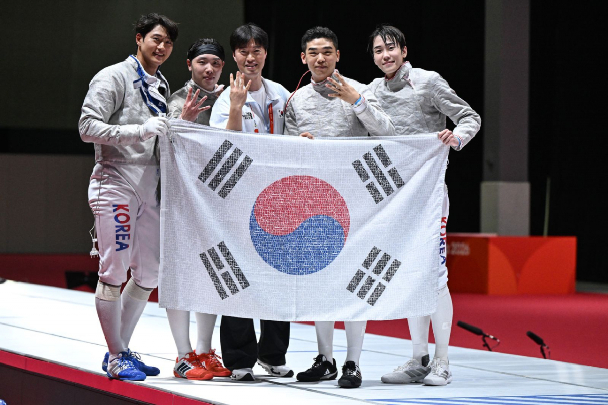 2026 아이치·나고야 아시안게임 펜싱 남자 사브르 단체전에서 대회 4연패를 달성한 한국 대표팀이 SK텔레콤 독자 AI 'A.X K2'로 국민 응원 메시지를 엮어 만든 '국민응원 태극기'를 들고 4연패를 뜻하는 손가락 네 개를 펴 보이며 기념 촬영을 하고 있다./사진 제공=SK텔레콤