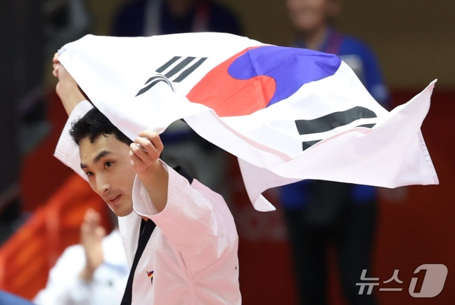 윤규성이 1일 일본 아이치현 도요하시 체육관에서 열린 2026 아이치·나고야 아시안게임 태권도 남자 개인 품새 메달 결승에서 우승을 차지하고 태극기를 들고 세리머니를 하고 있다. /사진=뉴스1