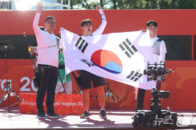 김우진(왼쪽부터), 김제덕, 이우석이 2일 일본 아이치현 오카자키시 오카자키 중앙종합공원 내 다목적 광장에서 열린 2026 아이치·나고야 아시안게임 양궁 리커브 남자 단체 결승에서 인도를 꺾고 태극기를 펼치고 세리머니를 하고 있다. /사진=뉴스1