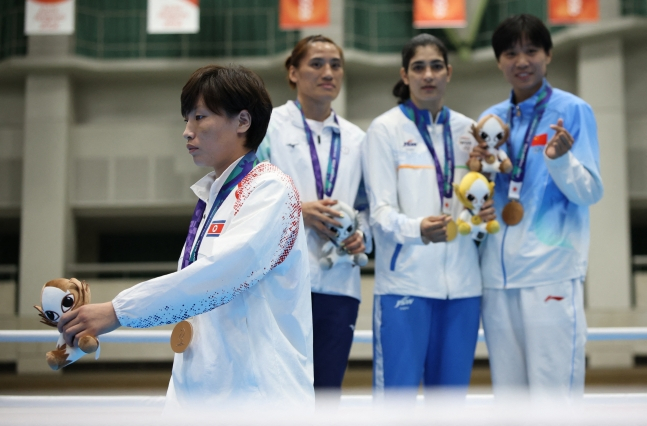북한 복서 황효선(왼쪽)이 2일 아이치현 니시오시 종합체육관에서 열린 2026 아이치·나고야 아시안게임 복싱 여자 65㎏급 시상식에서 동메달을 획득한 뒤 메달리스트 기념촬영을 보이콧하고 경기장을 빠져나가고 있다. /사진=로이터